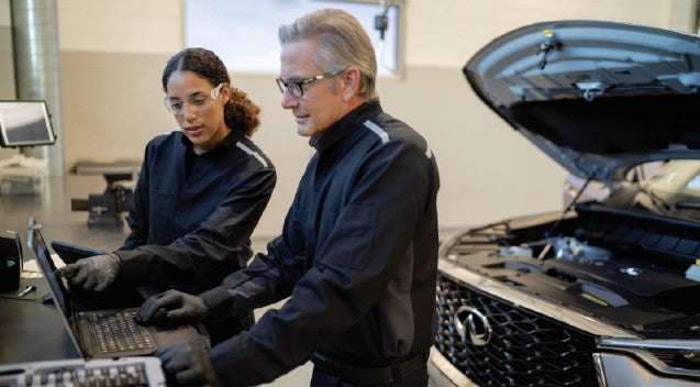INFINITI service experts looking at laptop